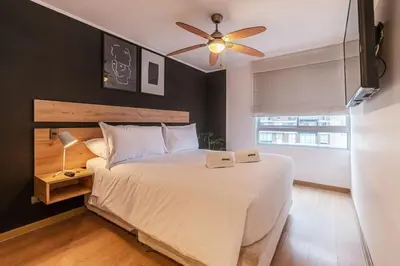 a bedroom with a white bed with a ceiling fan at Midnight District Apartment by Geko in Lima