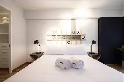 a bedroom with a large white bed with two towels at Soho by Geko in Lima