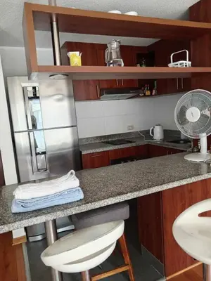 a kitchen with a counter with a fan and a refrigerator at Departamento amoblado vacacional in Lima
