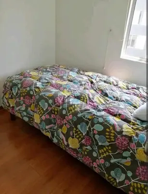 a bed with a colorful comforter in a room at Departamento amoblado vacacional in Lima