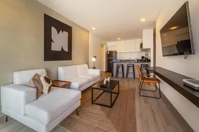a living room with a white couch and a kitchen at Sahara Sunset 2BR by Geko in Lima