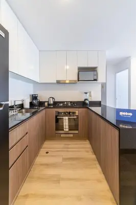 a kitchen with white cabinets and a wooden floor at Sahara Sunset 2BR by Geko in Lima