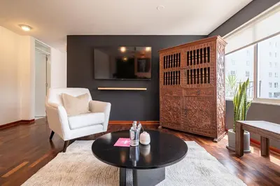 a living room with a white chair and a table at The Kennedy 3BR by Geko in Lima