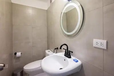a bathroom with a sink and a toilet and a mirror at The Kennedy 3BR by Geko in Lima