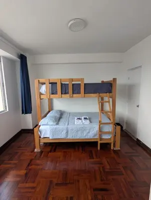 a bedroom with two bunk beds and a wooden floor at Amplia habitación en centro de Lima in Lima
