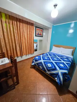 a bedroom with a bed and a table and a blue wall at Hospedaje Leo in Lima