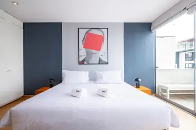 a bedroom with a large white bed with blue walls at Dopamine Duplex by Geko in Lima