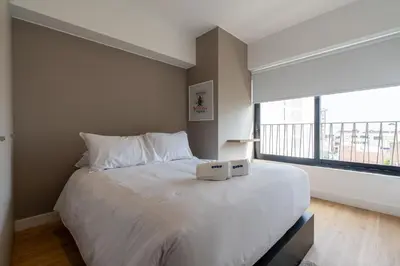a bedroom with a large white bed with a large window at Francia by Geko in Lima