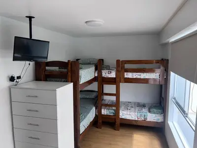 a bedroom with bunk beds and a dresser with a television at Alquilo Departamento en Playa Pulpos in Lurín