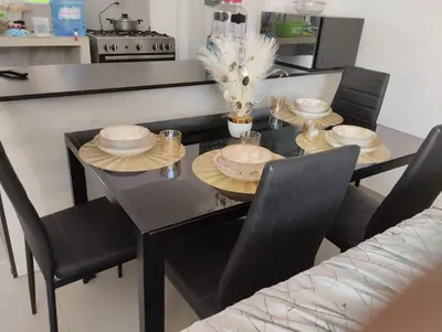 a black dining room table with black chairs and plates on it at Acogedora casa en ICA - PERU in Ica