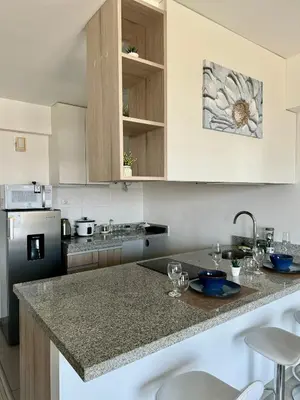 a kitchen with white cabinets and a counter top at Loft Ale Piso 22 in Lima