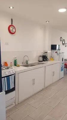 a kitchen with white cabinets and a sink and a stove at Casa Sunampe Chincha - 2do Piso in Sunampe