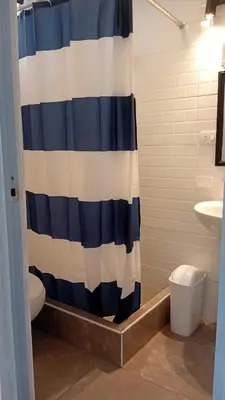 a bathroom with a blue and white shower curtain at Casa Sunampe Chincha - 2do Piso in Sunampe