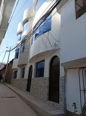 a white building with arched windows on a street at Ankay House in Cusco