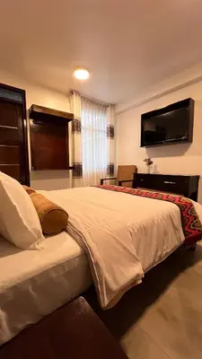 a bedroom with a large bed and a flat screen tv at Hospedaje Turístico - Kantu Inn in Ollantaytambo
