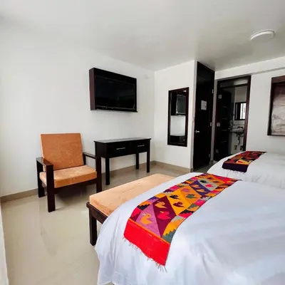 a bedroom with a bed and a chair and a television at Hospedaje Turístico - Kantu Inn in Ollantaytambo