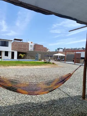 a hammock on the ground with a building in the background at casa de playa en lurin con piscina y parrilla in La Planicie