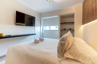 a bedroom with a white bed with a flat screen tv at Grimaldo by Geko in Lima