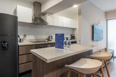 a kitchen with a counter with stools and a refrigerator at Grimaldo by Geko in Lima