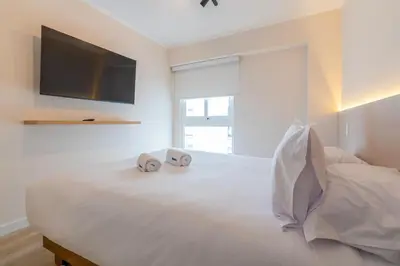a bedroom with a white bed with two clocks on it at Samoa 1BR by Geko in Lima