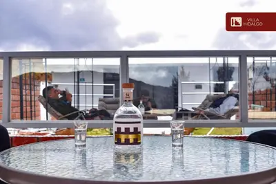 a bottle of alcohol sitting on a table with two glasses at Villa Hidalgo - Centro Vacacional in Pazos