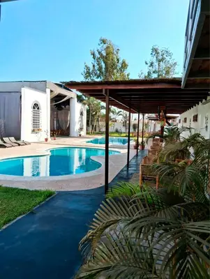 a swimming pool with a pavilion next to a building at Punto Sur Lodge - Chincha in Chincha Alta