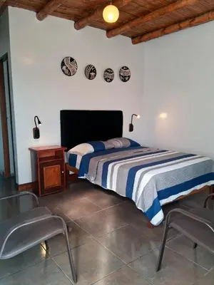 a bedroom with a bed and a table and chairs at Punto Sur Lodge - Chincha in Chincha Alta