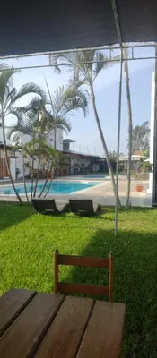 a wooden bench sitting under a tent next to a pool at Punto Sur Lodge - Chincha in Chincha Alta