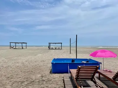 a beach with two chairs and an umbrella and two swings at Casa de playa en Wakama in San Vicente de Cañete