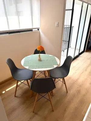 a table with chairs and a vase with flowers on it at Céntrico y acogedor apartamento en Lince in Lima