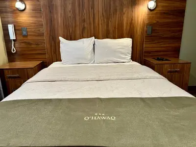 a bed with white pillows and wooden walls in a room at Hotel Qhawaq Huancayo in Huancayo
