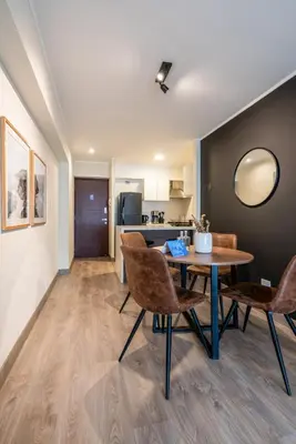a dining room with a table and chairs and a kitchen at The Oak 2BR by Geko in Lima
