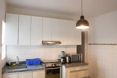 a kitchen with white cabinets and a sink and a microwave at Casa en el corazón de Miraflores in Lima
