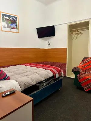 a bedroom with a bed and a tv on the wall at Posada Escondida in Cusco