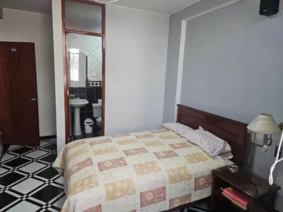 a bedroom with a bed and a bathroom with a sink at Hotel Atenas in Lima