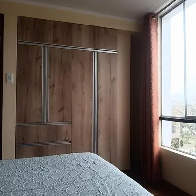 a bedroom with a wooden cabinet and a bed at Bonito Departamento Lima Carabayllo in Lima