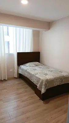 a bedroom with a bed and a large window at Tu mejor opción Departamento Familiar in Lima
