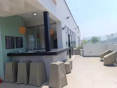a building with a counter with a sink and stools at Tu mejor opción Departamento Familiar in Lima