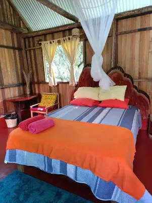 a bedroom with a bed with an orange and blue blanket at Bella Victoria Ecolodge in Santa María