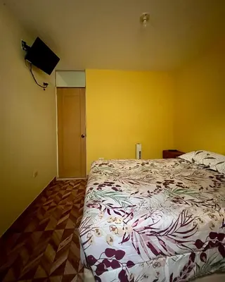 a bedroom with a bed and a yellow wall at Paracas Ayni in Paracas