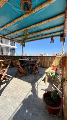 a patio with a table and chairs and a blue umbrella at Paracas Ayni in Paracas