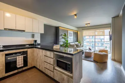 a kitchen with a counter and a living room at Stelar by Geko in Lima