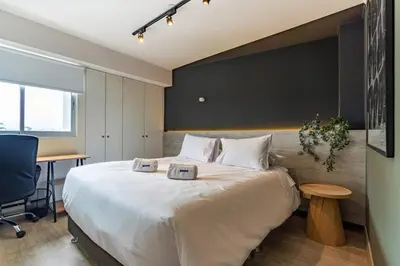 a bedroom with a large white bed and a desk at Stelar by Geko in Lima