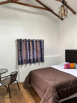 a bedroom with a bed and a chair and a window at Auquis Hostel in Cusco