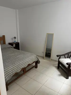 a bedroom with a bed and a mirror and a chair at Punta Hermosa - depa Santa Cruz in Punta Hermosa