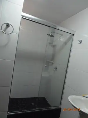 a shower with a glass door next to a sink at B&B Cusing Wasi in Lima