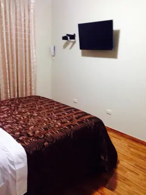 a bedroom with a bed and a flat screen tv at B&B Cusing Wasi in Lima
