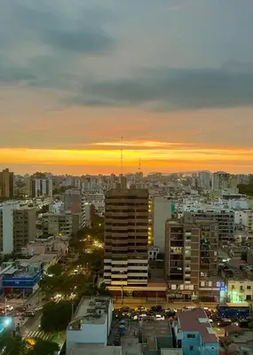 a view of a city at sunset with buildings at Encantador departamento con hermosa vista in Lima