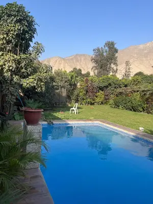 a swimming pool in a yard with mountains in the background at casa de campo en cieneguilla in Cieneguilla