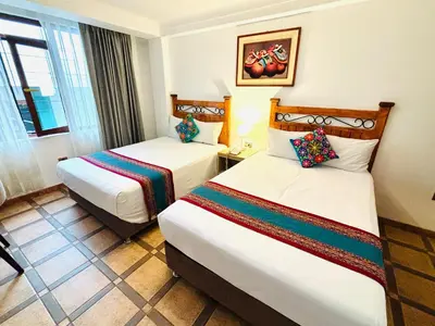 a hotel room with two beds and a window at Hotel Rojas Machupicchu in Machu Picchu